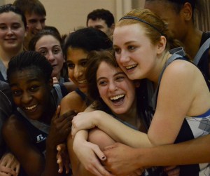 A group of young female basketballs hug after a win.